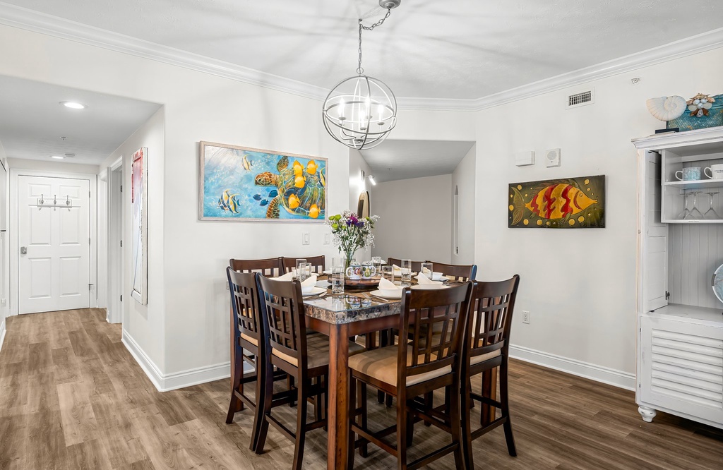 Dining area with a wooden table and seating for eight under a modern light fixture.