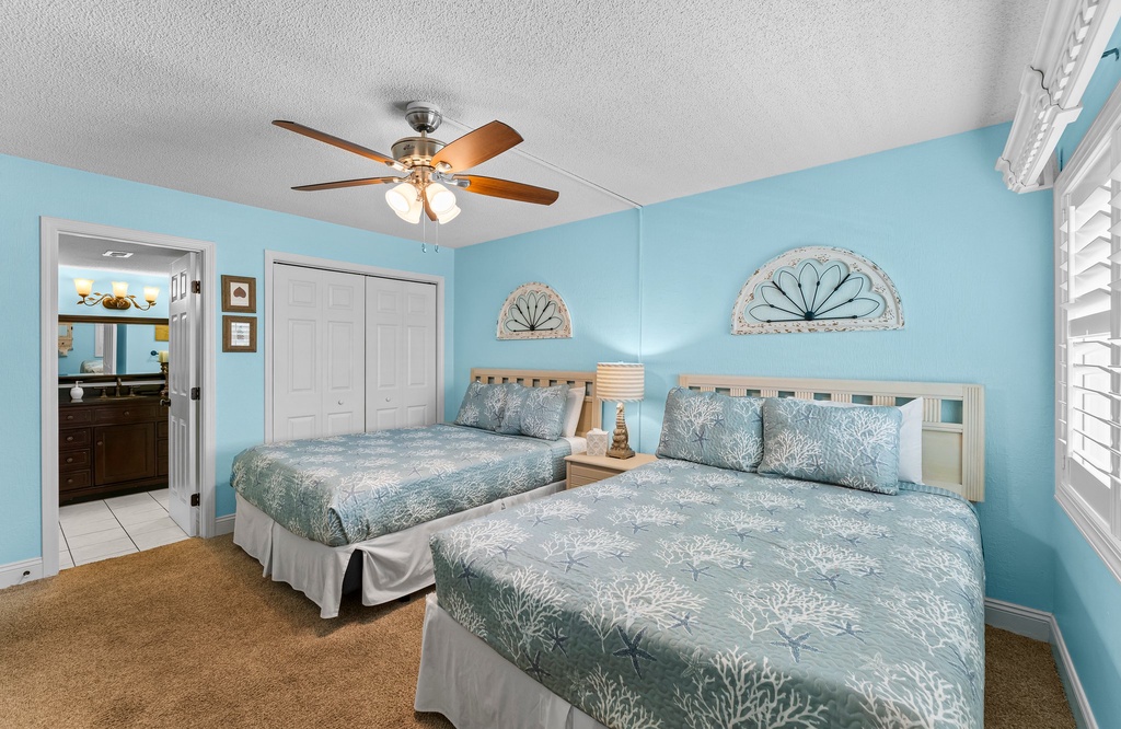 Bedroom w/ two beds & a ceiling fan, ideal for a restful night's sleep.