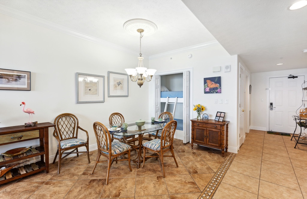 Dining area with a glass table and rattan chairs in a bright, tiled room