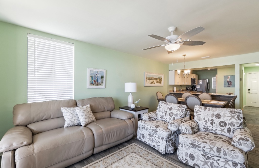 Unwind in your spacious living room featuring plush seating and coastal charm, with an open-concept flow to the full kitchen.