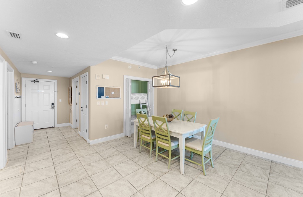 Dining area with a modern light fixture and colorful chairs for family meals.