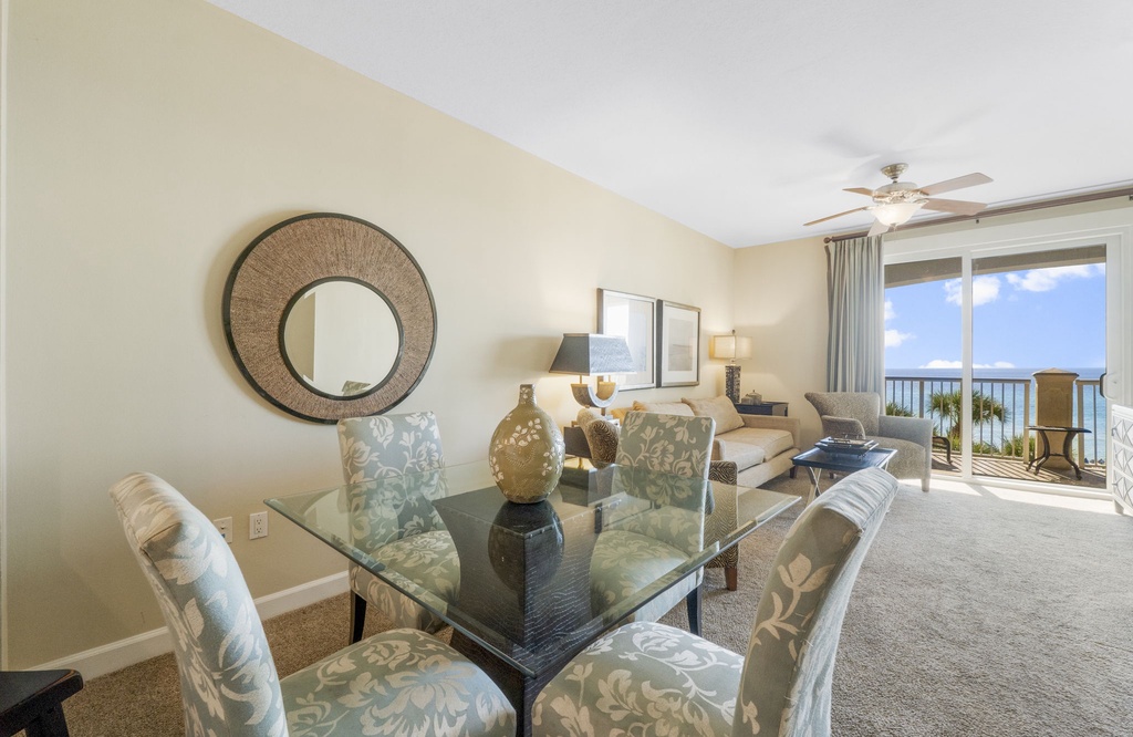 Relax in this bright living and dining area with ocean views and access to a balcony.