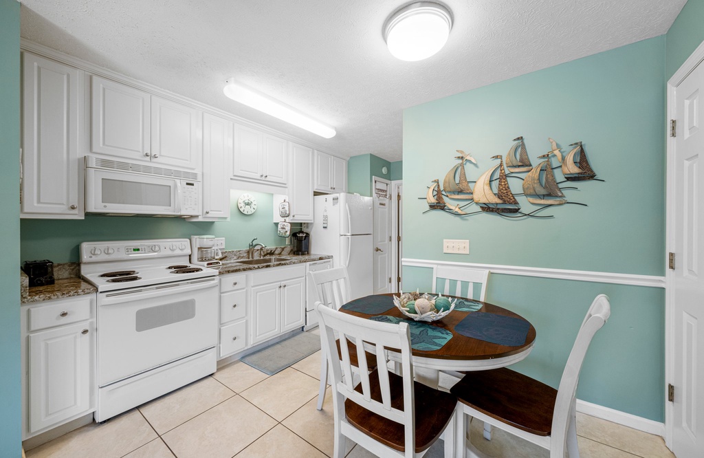Cheerful kitchen & dining area w/ white cabinets, full appliances & a cozy table for meals.