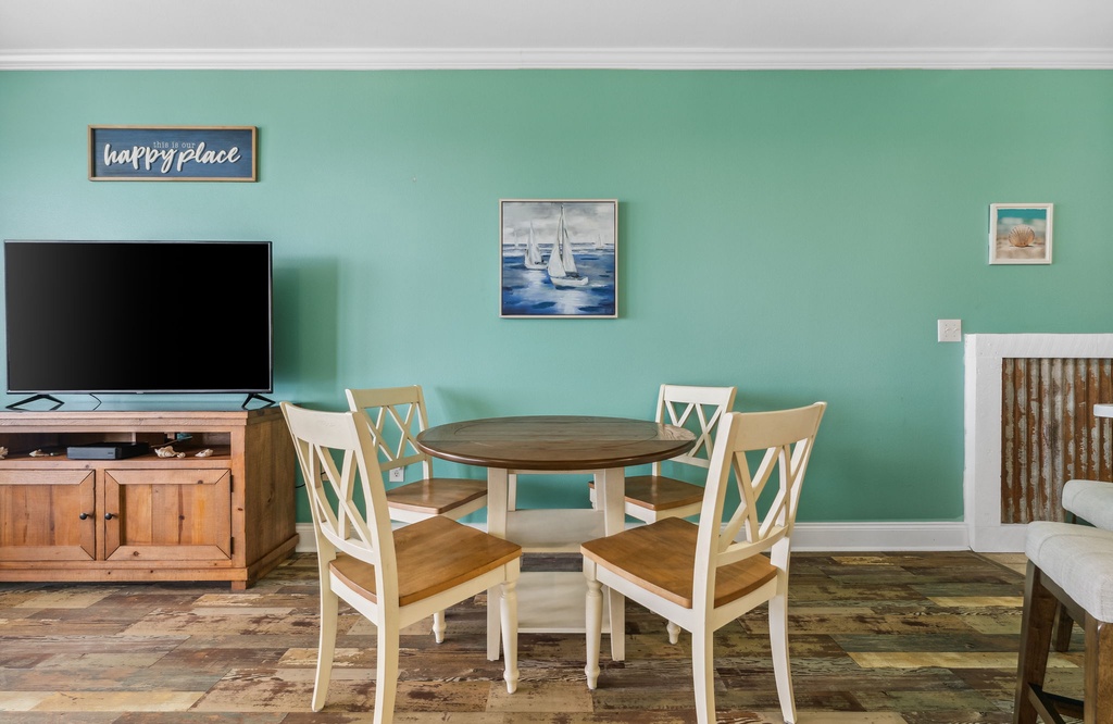 Cozy dining area with a round wooden table and four chairs against a soft green wall.