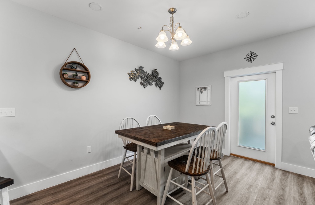 dining area with rustic wooden table and white chairs next to a frosted glass door