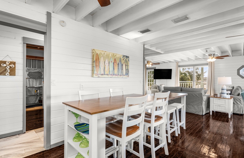 Open-concept dining and living area with rustic wood floors and coastal decor.