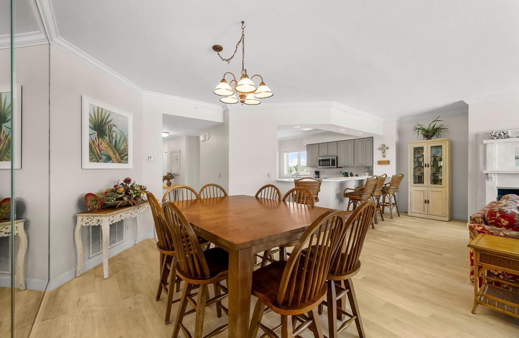 Spacious dining area with wooden table and chairs adjacent to a modern kitchen with bar seating.