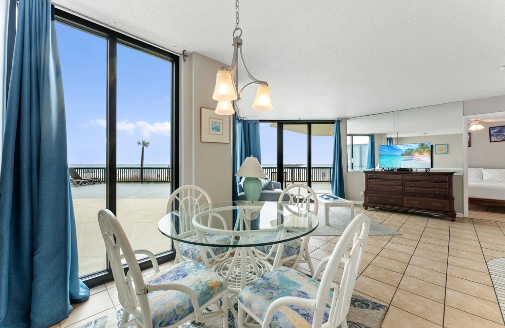 Dining area with glass table and ocean views through large sliding doors