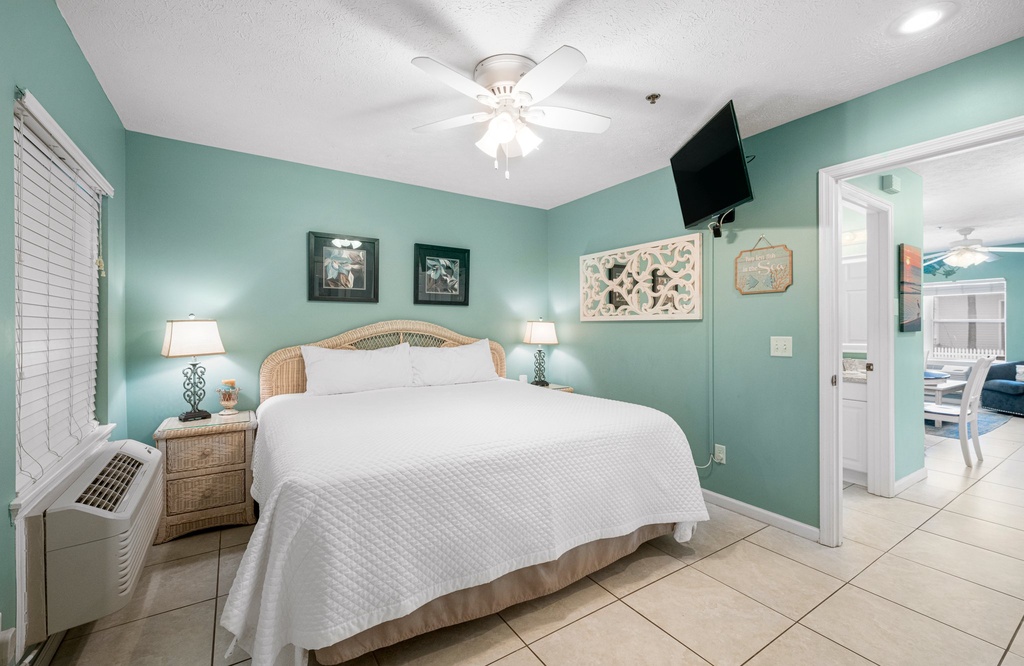 Restful primary bedroom w/ a plush bed, ceiling fan & soft natural light.