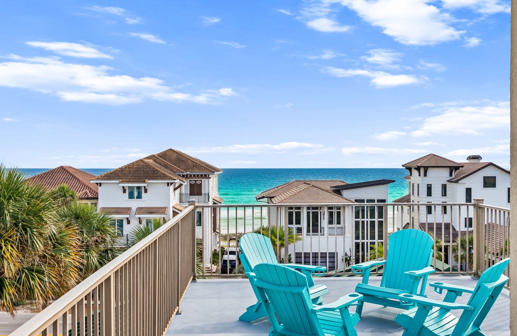 Settle into a sunny afternoon on your private terrace, where turquoise chairs frame sweeping views of the sparkling Gulf waters and soft white sand—your perfect escape, just steps away.