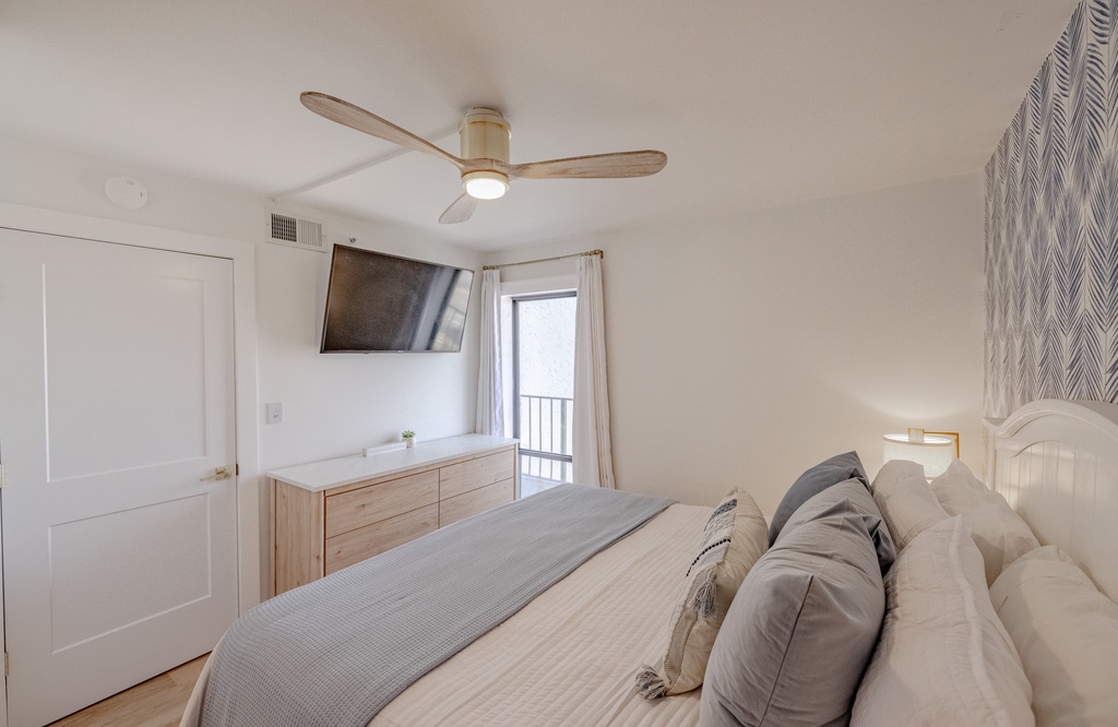 Modern bedroom with a ceiling fan and wall-mounted television for comfortable relaxation.