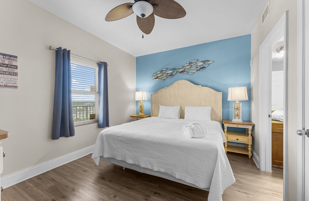 Relax in this bright bedroom featuring a coastal blue accent wall and natural light.