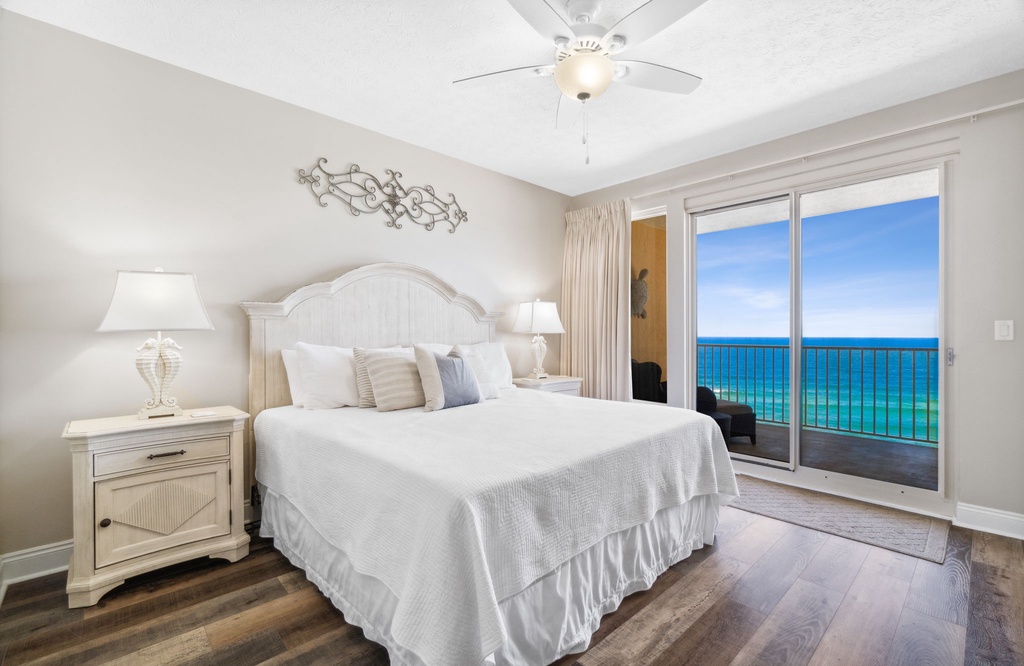 Primary bedroom w/ a cozy bed & sweeping ocean views right from the pillow.
