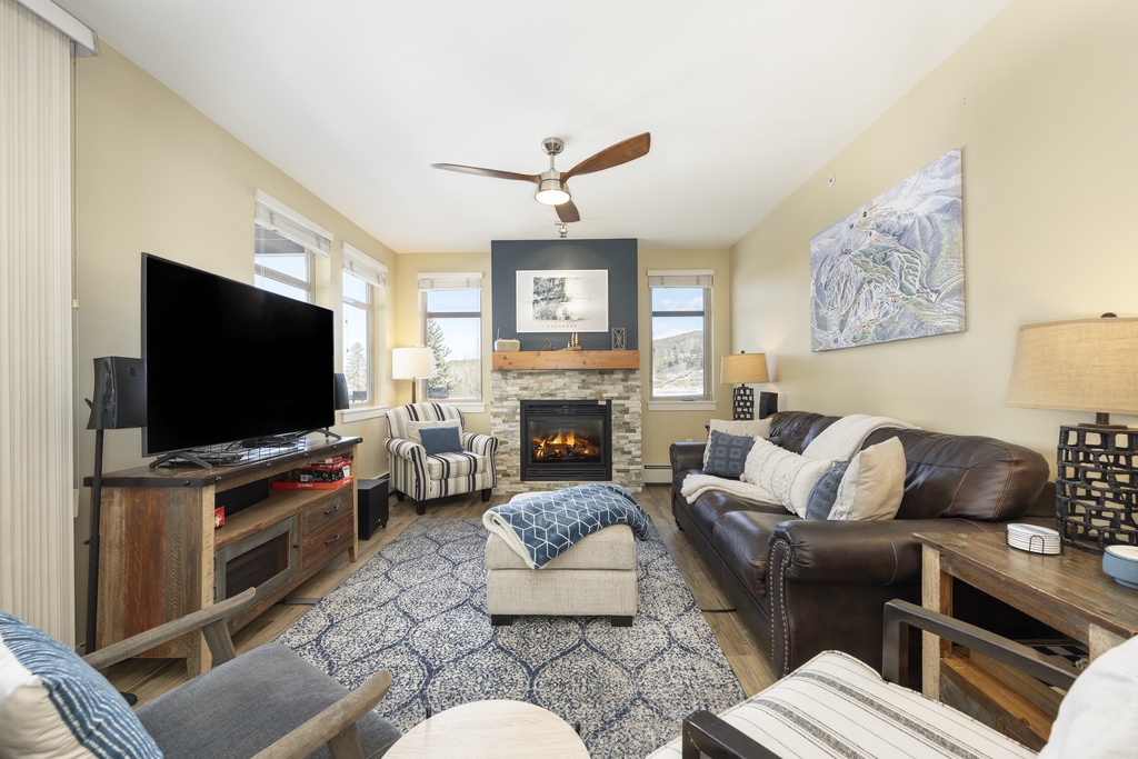Relax in your cozy living room with a crackling fireplace, comfortable leather seating, and mountain views through large windows.