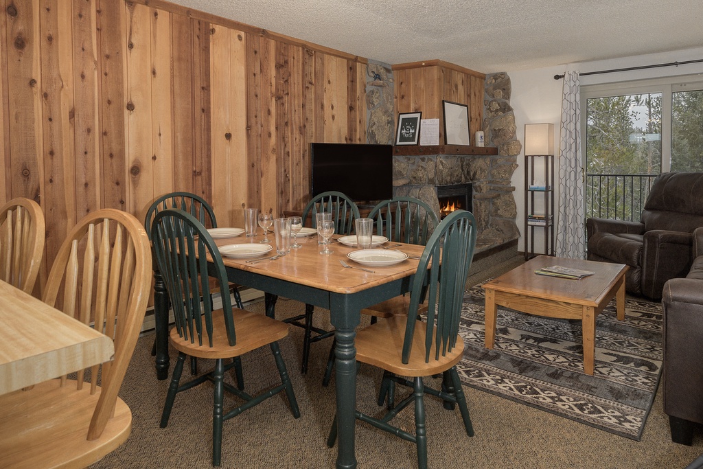 Gather around your cozy dining table with warm wood walls and crackling fireplace creating the perfect mountain retreat atmosphere.