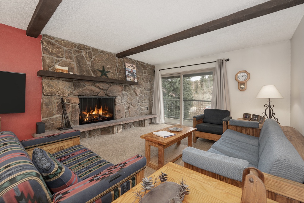 Cozy up by your crackling stone fireplace after mountain adventures, surrounded by comfortable seating and rustic charm.