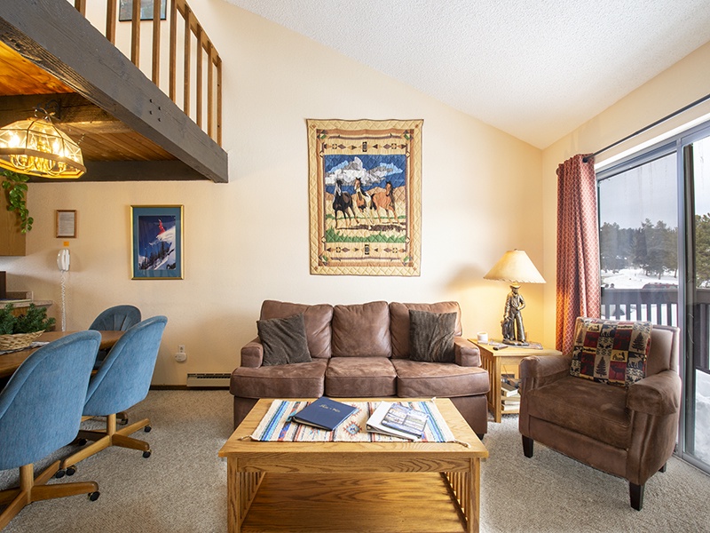 Relax in your cozy living space with plush seating, warm lighting, and mountain views through the large windows.