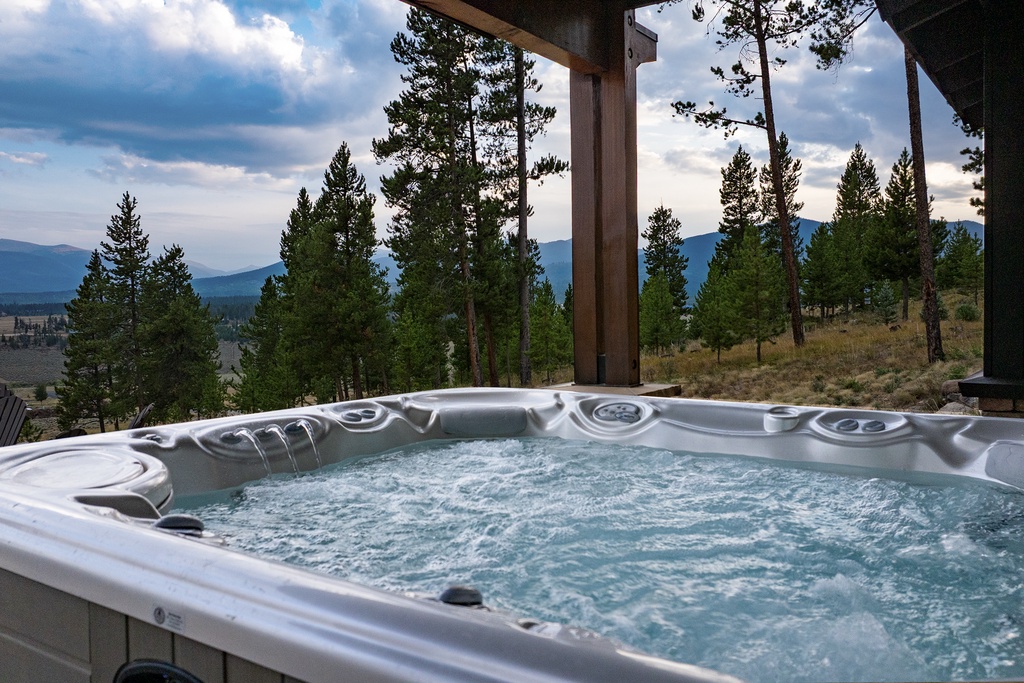 Soak in the bubbling warmth as you gaze across pine-dotted slopes and distant mountain peaks—your private escape where relaxation meets breathtaking wilderness views.