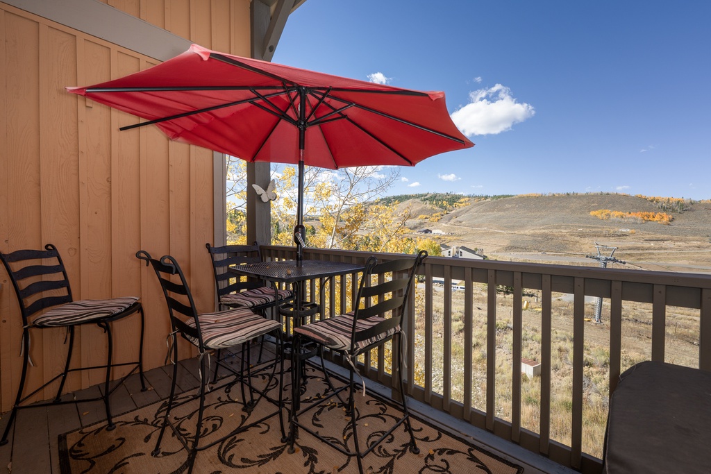 Your private balcony offers breathtaking mountain views with comfortable seating and shade for perfect outdoor dining moments at Kicking Horse Palomino 7-302.