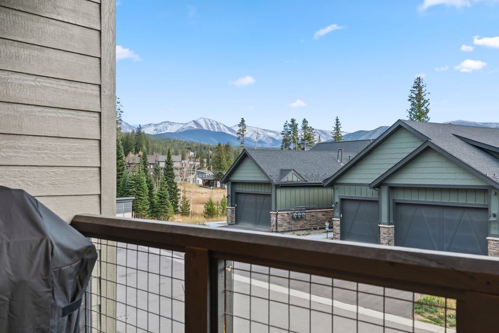 Mountain resort community with dramatic peaks framing modern homes and forested surroundings under blue skies.