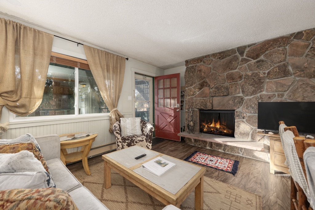 Cozy up by your crackling stone fireplace after mountain adventures. This rustic living room wraps you in warmth and charm.