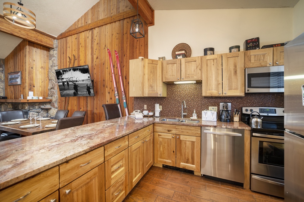 Your rustic alpine kitchen features granite counters, stainless appliances, and cozy wood accents perfect for preparing meals after skiing adventures.