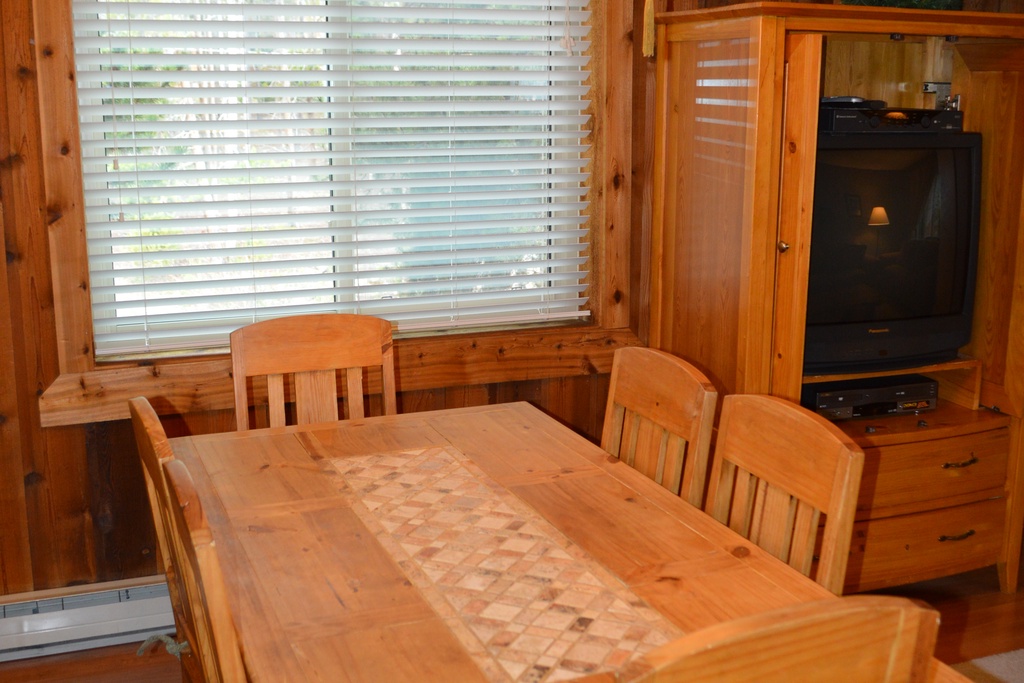 Cozy wood-paneled dining room with rustic charm. Gather around the handcrafted table for meals while enjoying mountain cabin ambiance.
