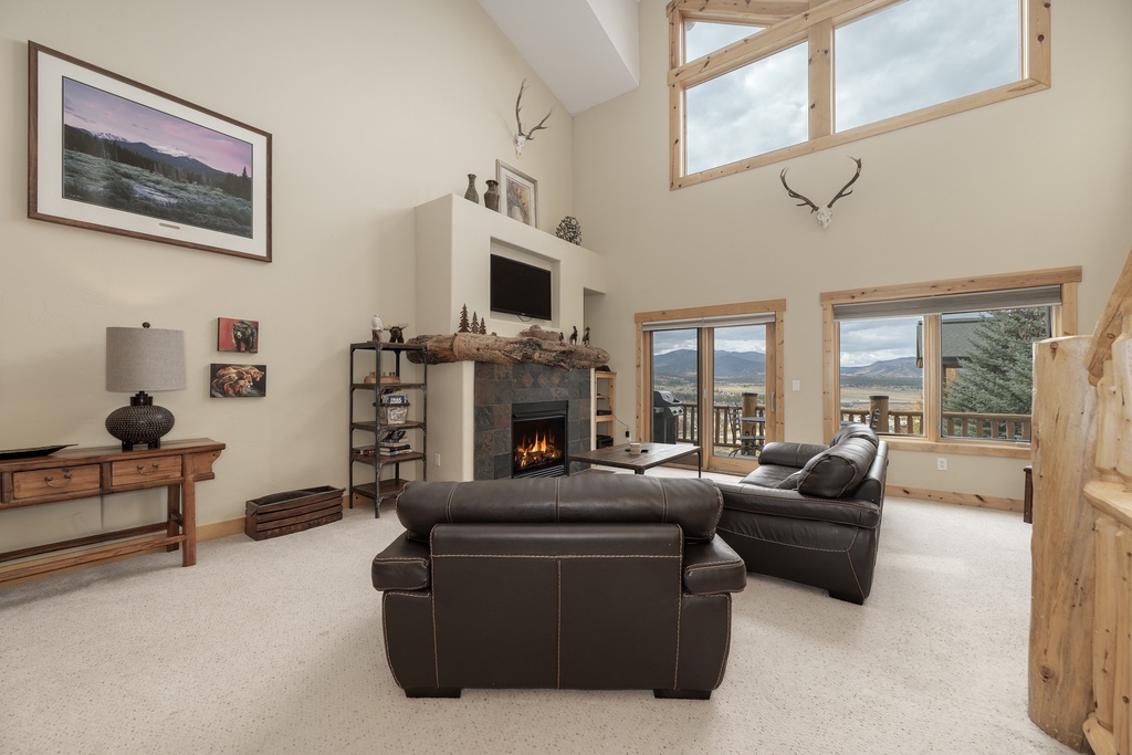 Unwind by the crackling fireplace while mountain views stretch beyond the windows in this cozy living room.