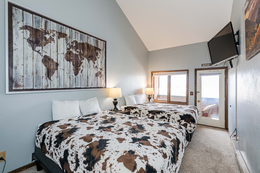 Rest easy in your comfortable bedroom featuring queen beds, modern amenities, and a charming world map that sparks wanderlust dreams.