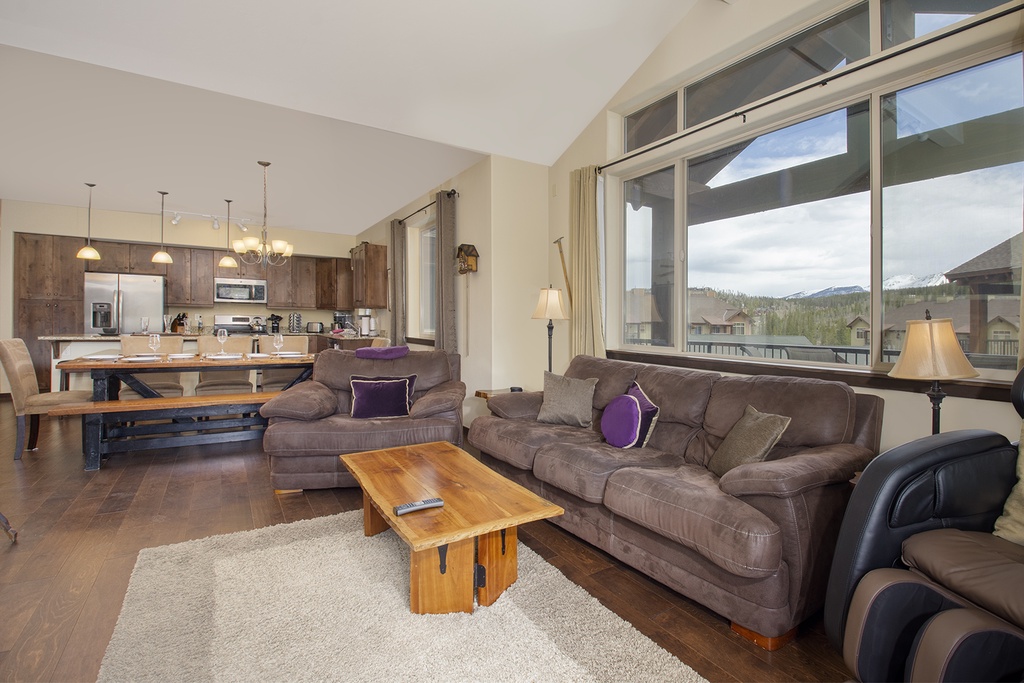 Relax in your spacious open-concept living area with mountain views through floor-to-ceiling windows while you unwind on the plush sectional sofa.