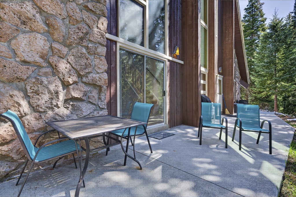 Step out onto your private patio, where mountain air meets rustic stone charm and turquoise seating invites you to linger over morning coffee surrounded by towering pines.