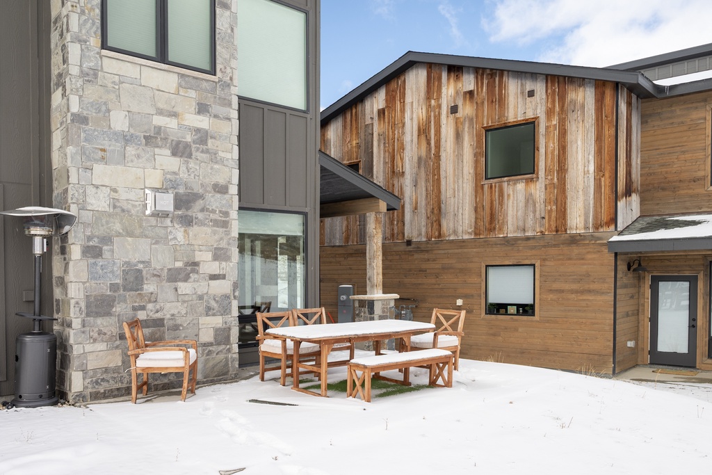 Modern mountain retreat at Base Camp Townhome 106 featuring stone and wood architecture with private outdoor dining space.