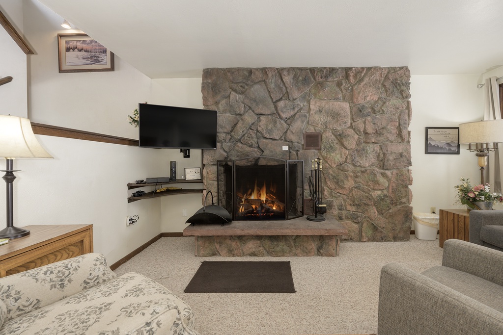 Cozy up in your inviting living room featuring a beautiful stone fireplace, perfect for romantic evenings with crackling flames and comfortable seating.