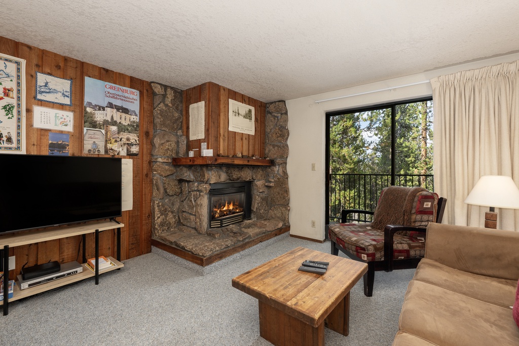 Cozy up in your mountain retreat with a crackling stone fireplace, comfortable seating, and peaceful forest views from your private balcony.
