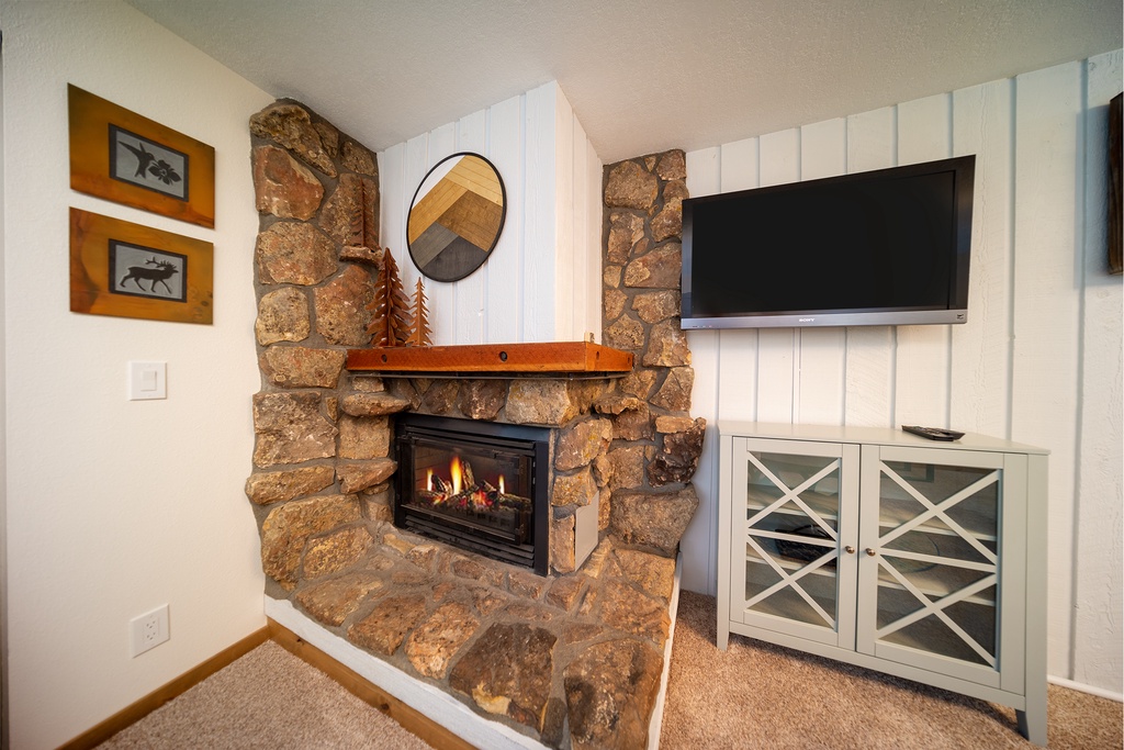 Cozy up by your stone fireplace with crackling flames while enjoying shows on the wall-mounted TV in this comfortable living space.