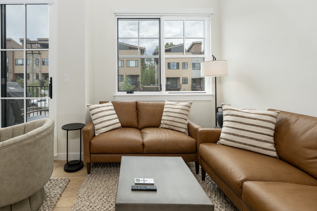 Sink into luxurious leather sofas in your bright living space, where large windows frame peaceful neighborhood views and modern comfort awaits.