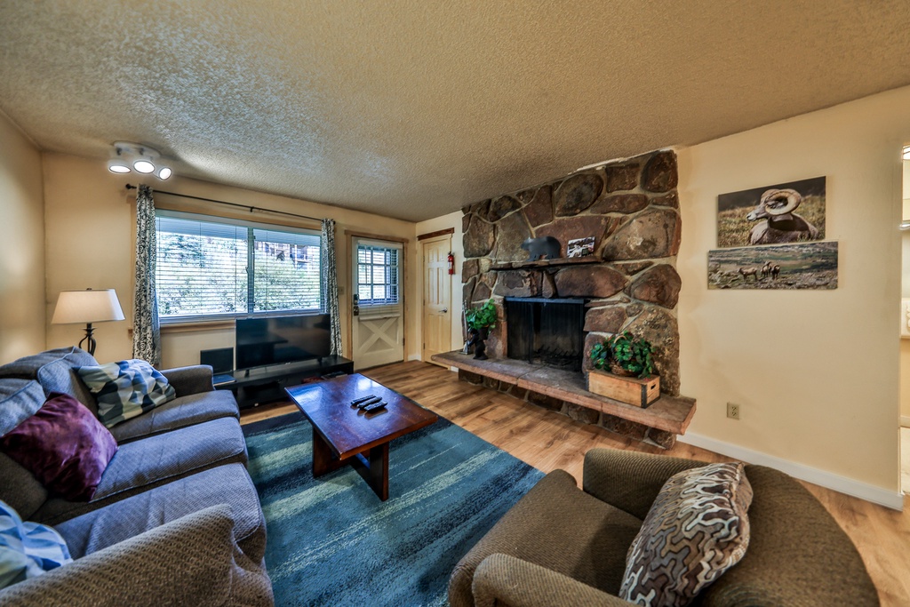 Cozy up by your rustic stone fireplace with plush seating and mountain art creating the perfect après-ski retreat.
