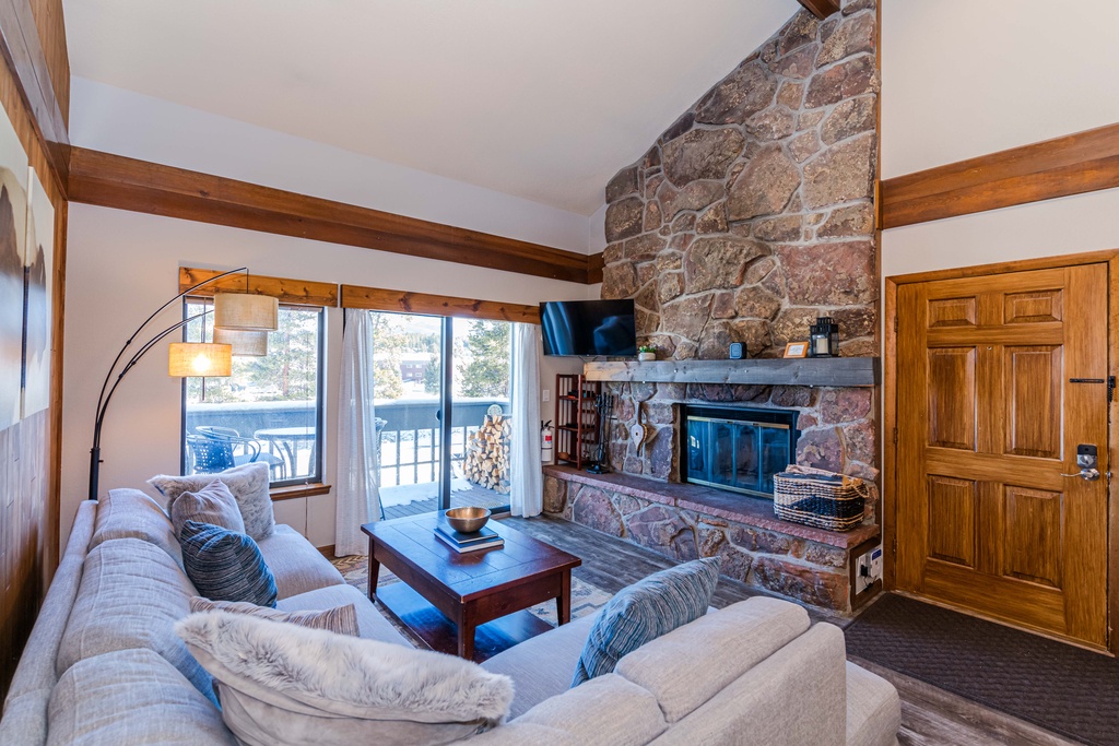 Cozy up by your stone fireplace in this warm living room, where rustic beams and soft seating create the perfect mountain retreat atmosphere.