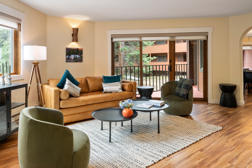 Unwind in your stylish living room with plush seating, warm wood floors, and a peaceful balcony view.
