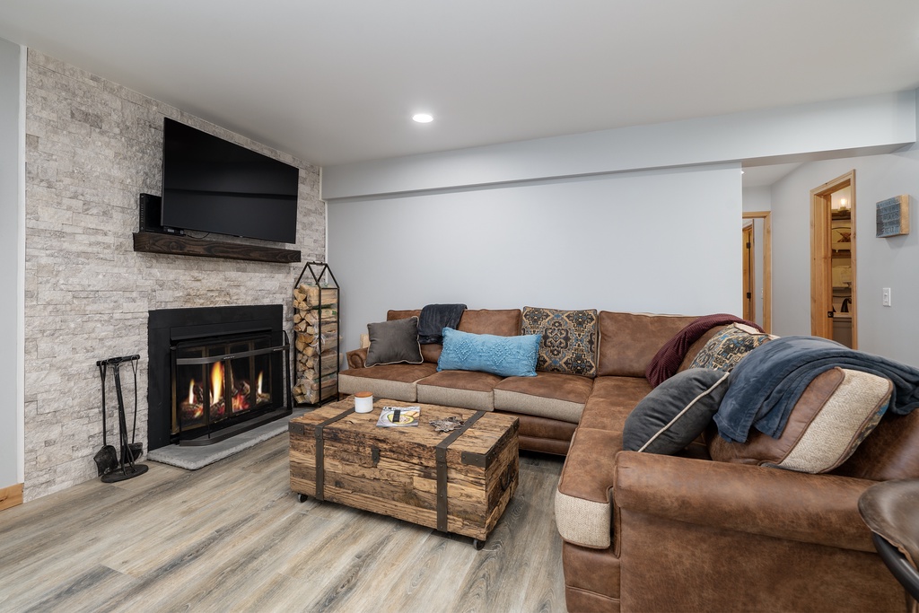 Unwind by the crackling fireplace in this cozy living space, where plush leather seating and warm lighting create your perfect retreat.