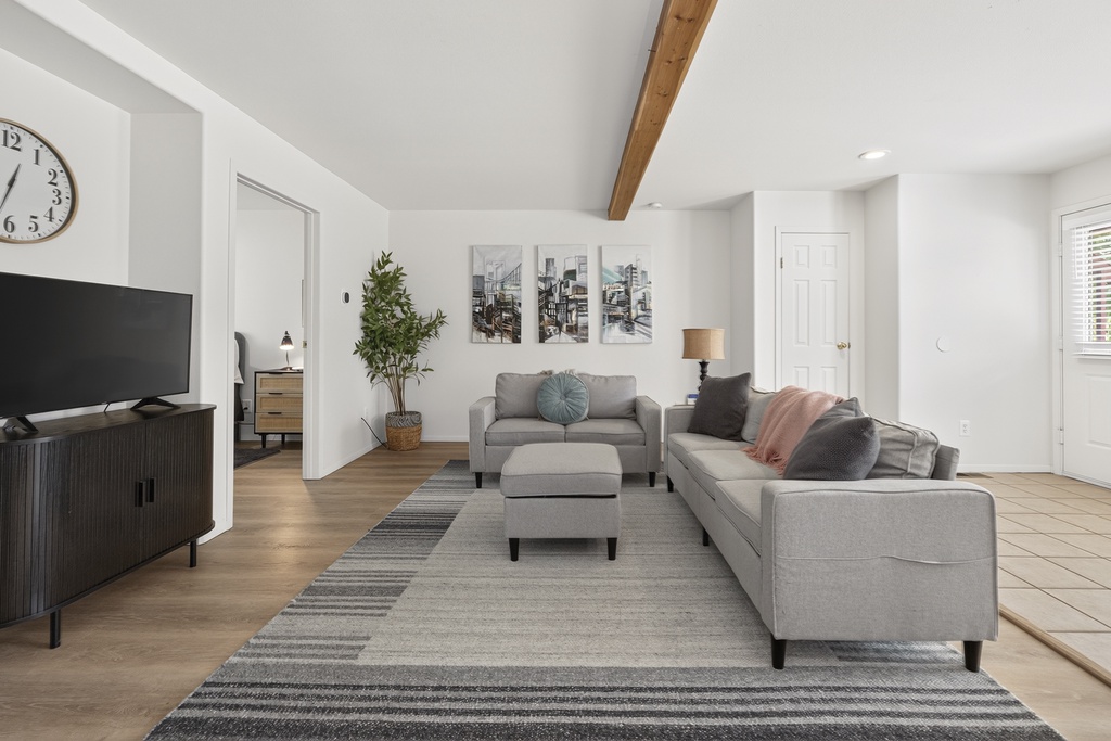 Sink into plush sofas and unwind in your bright, modern living space—high ceilings and warm wood beams create the perfect backdrop for relaxation after a day of exploring.