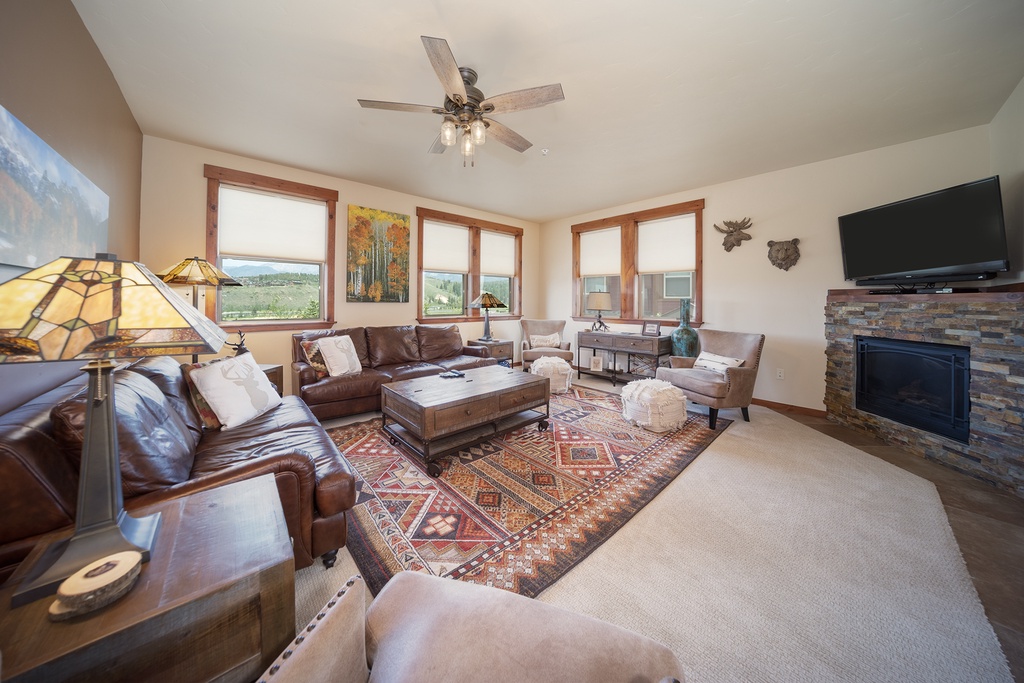 Settle into this warm living room with rich leather seating, crackling fireplace, and mountain views through every window.