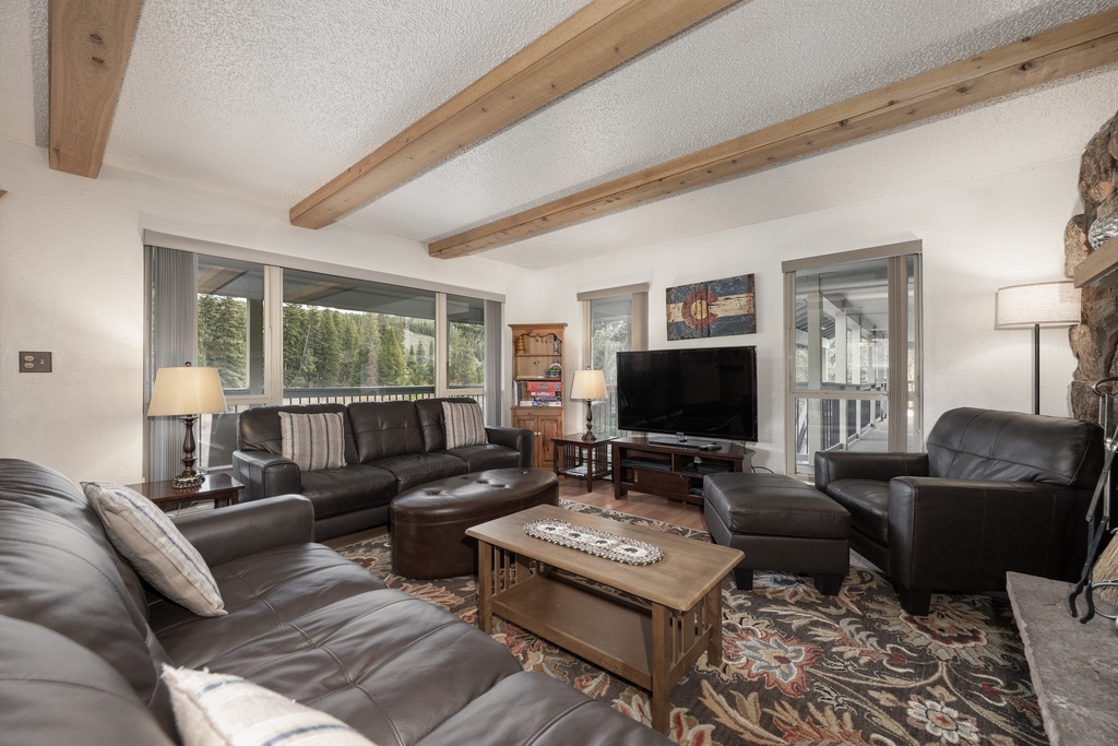 Settle into your spacious living room featuring rich leather seating, exposed wooden beams, and a cozy stone fireplace for perfect mountain evenings.