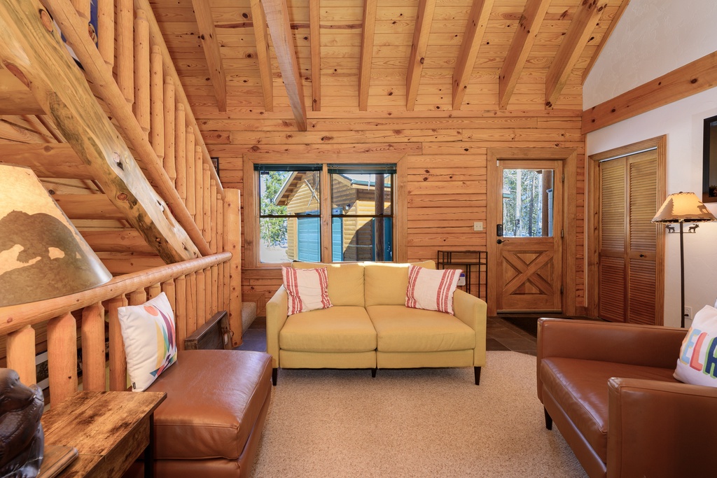 Unwind in your cozy cabin retreat with exposed beam ceilings and comfortable seating perfect for evening relaxation.
