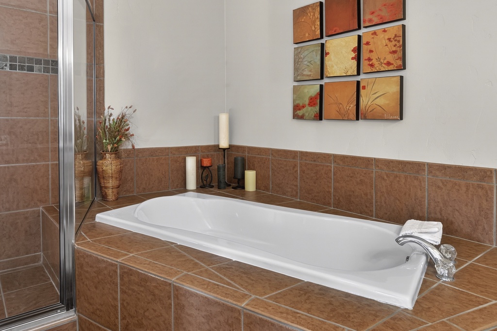Sink into your private soaking tub, surrounded by warm earth tones and flickering candlelight that transforms bath time into pure relaxation.