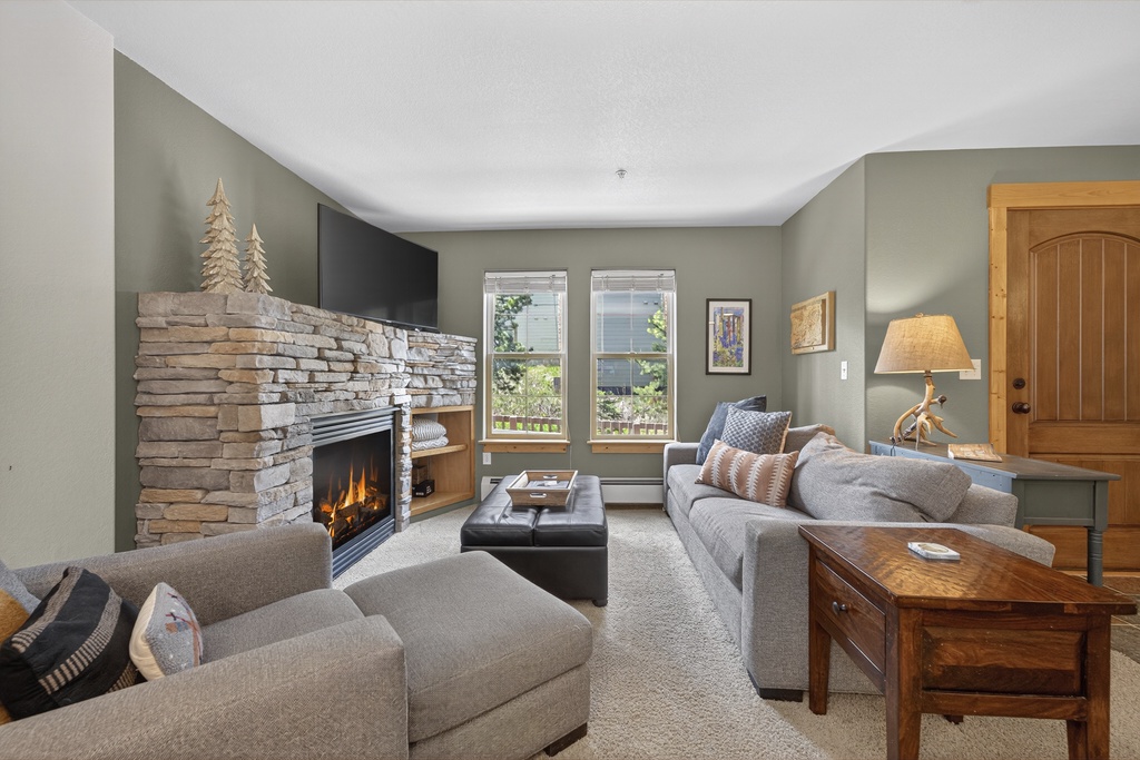 Unwind in your serene living room, where a crackling stone fireplace and plush seating create the perfect mountain retreat after a day of adventure.