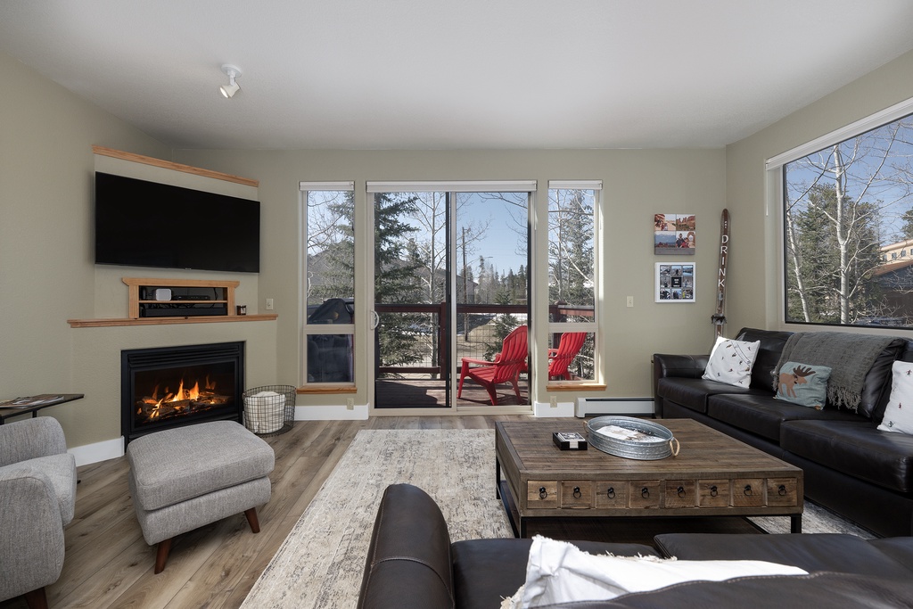 Unwind in your cozy living room where a crackling fireplace meets stunning mountain views through floor-to-ceiling windows.