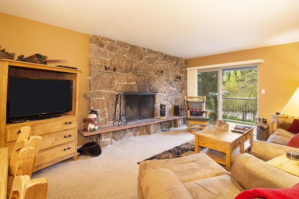 Cozy up by your stone fireplace while enjoying mountain views from this warm, inviting living space with rustic wood furnishings.