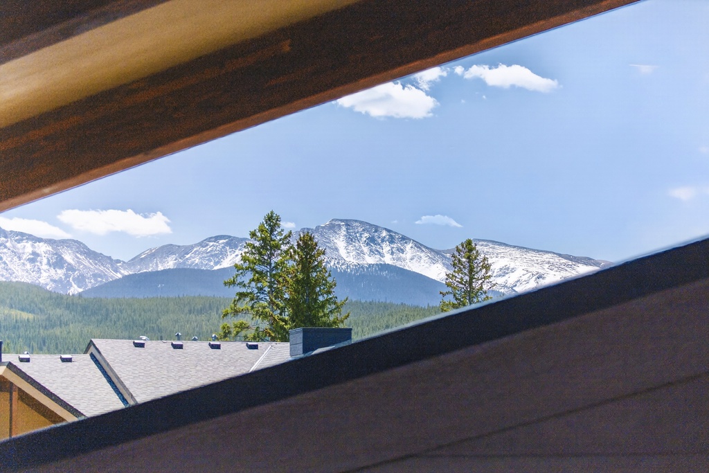 Spectacular mountain panorama frames snow-capped peaks and evergreen forests visible from this elevated vantage point.