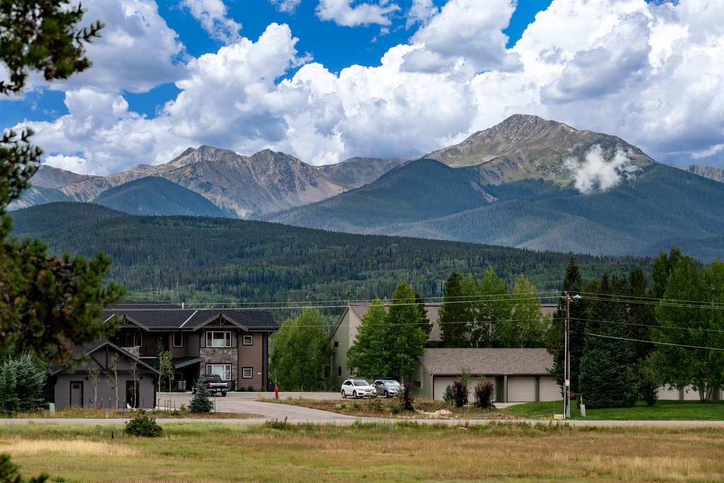 Mountain community nestled beneath dramatic peaks with residential neighborhoods surrounded by natural forest landscape.